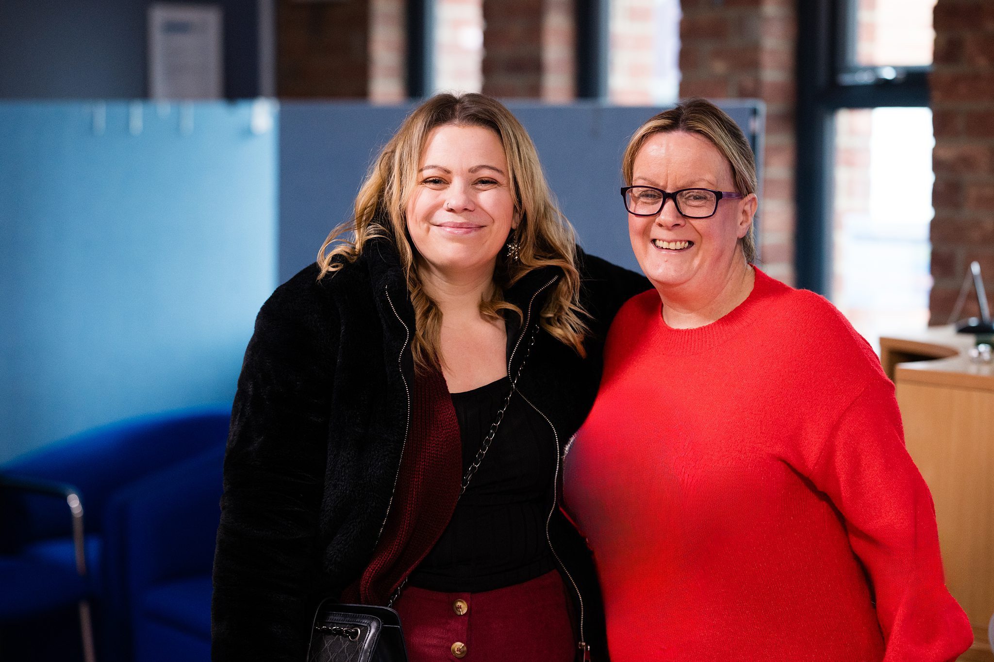 Two women shoulder to shoulder smiling
