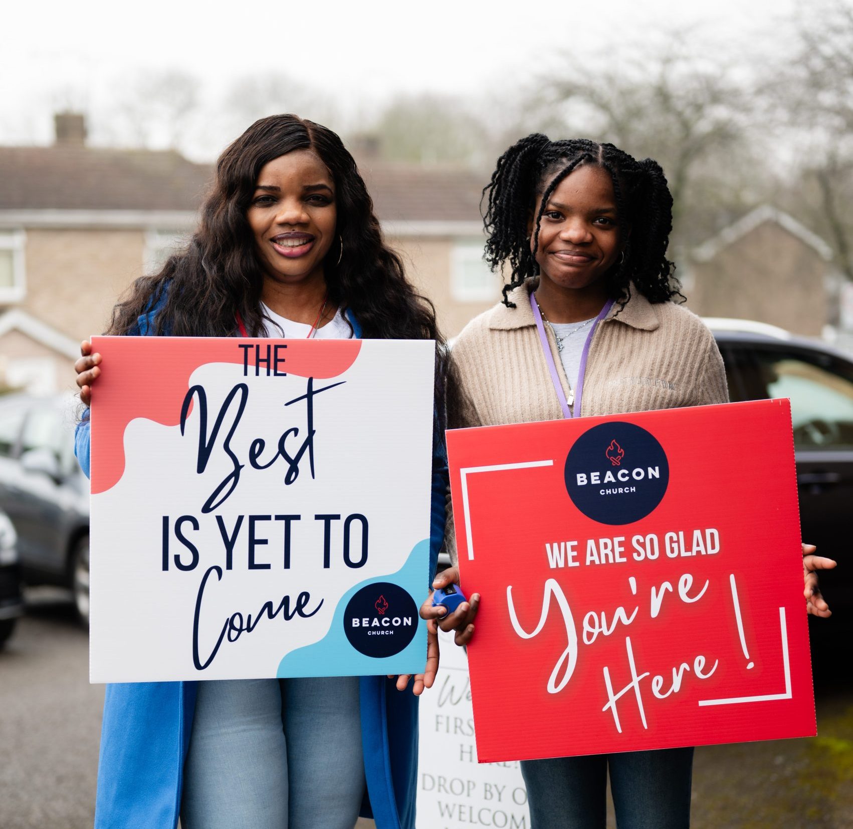 Two women holding welcome signs inviting people to church in Bury St Edmunds, Suffolk