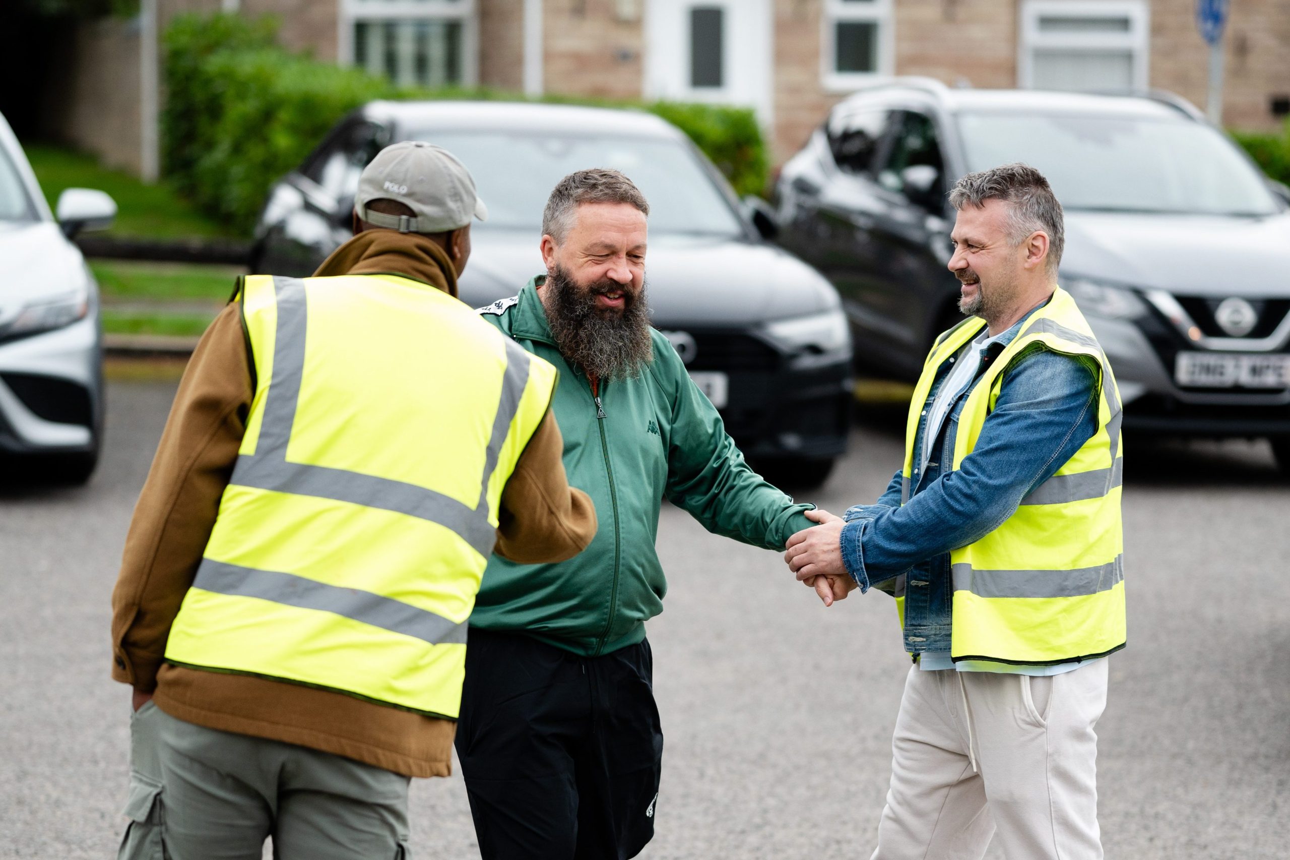 Three men greeting each other outdoors at a church community gathering in Bury St Edmunds, Suffolk.