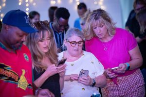 People gathered together engaging with phones and connecting at a church event in Bury St Edmunds, Suffolk