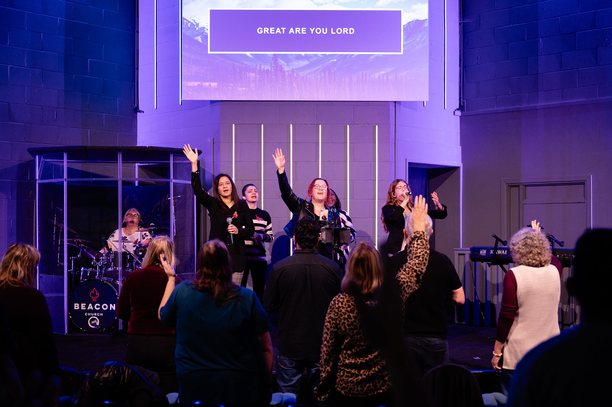People worshipping with raised hands during a live church service in Bury St Edmunds, Suffolk