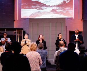 Worship band leading a live church service with people standing and singing in Bury St Edmunds, Suffolk