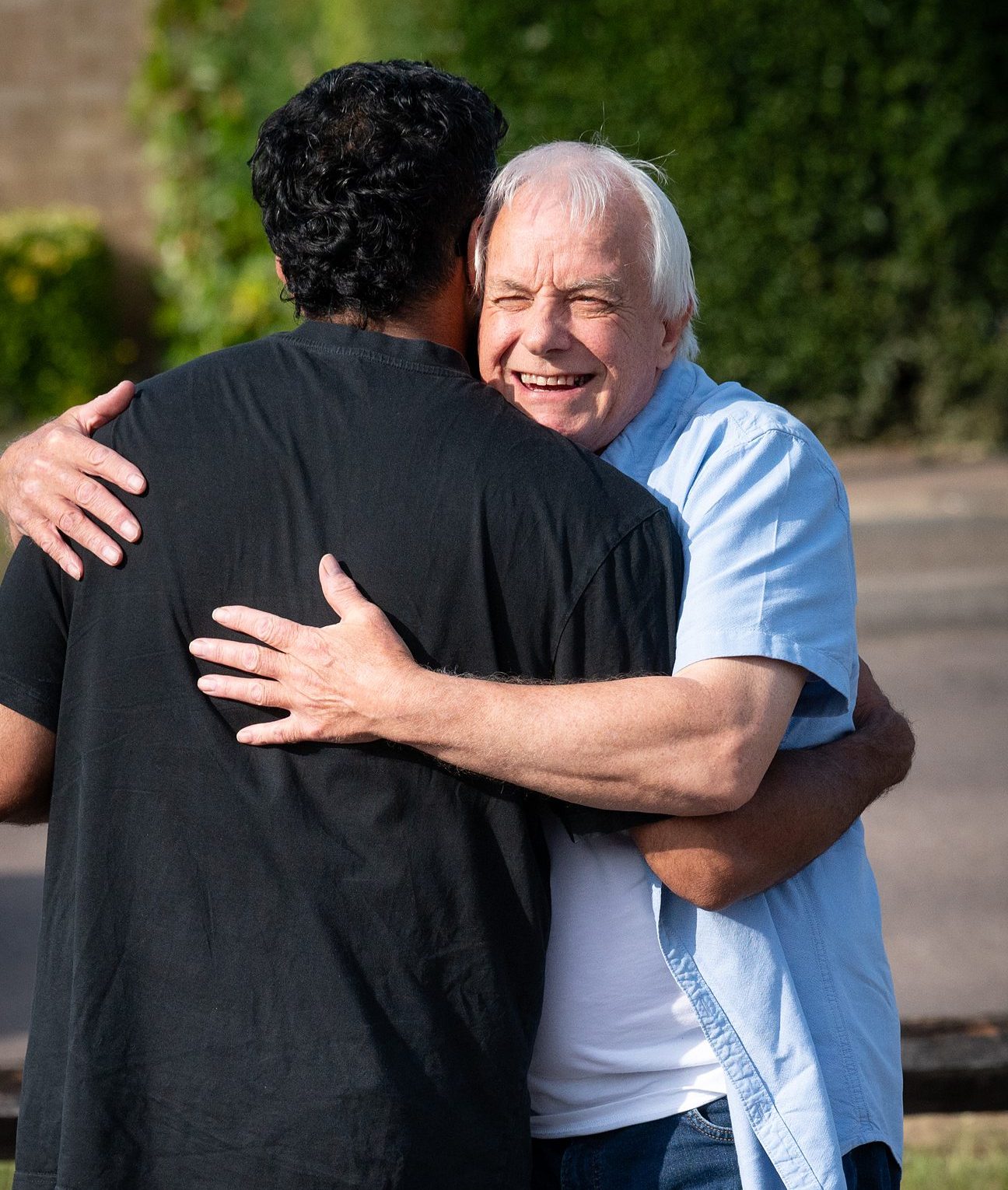 Two men sharing a warm embrace outside church in Bury St Edmunds, Suffolk.