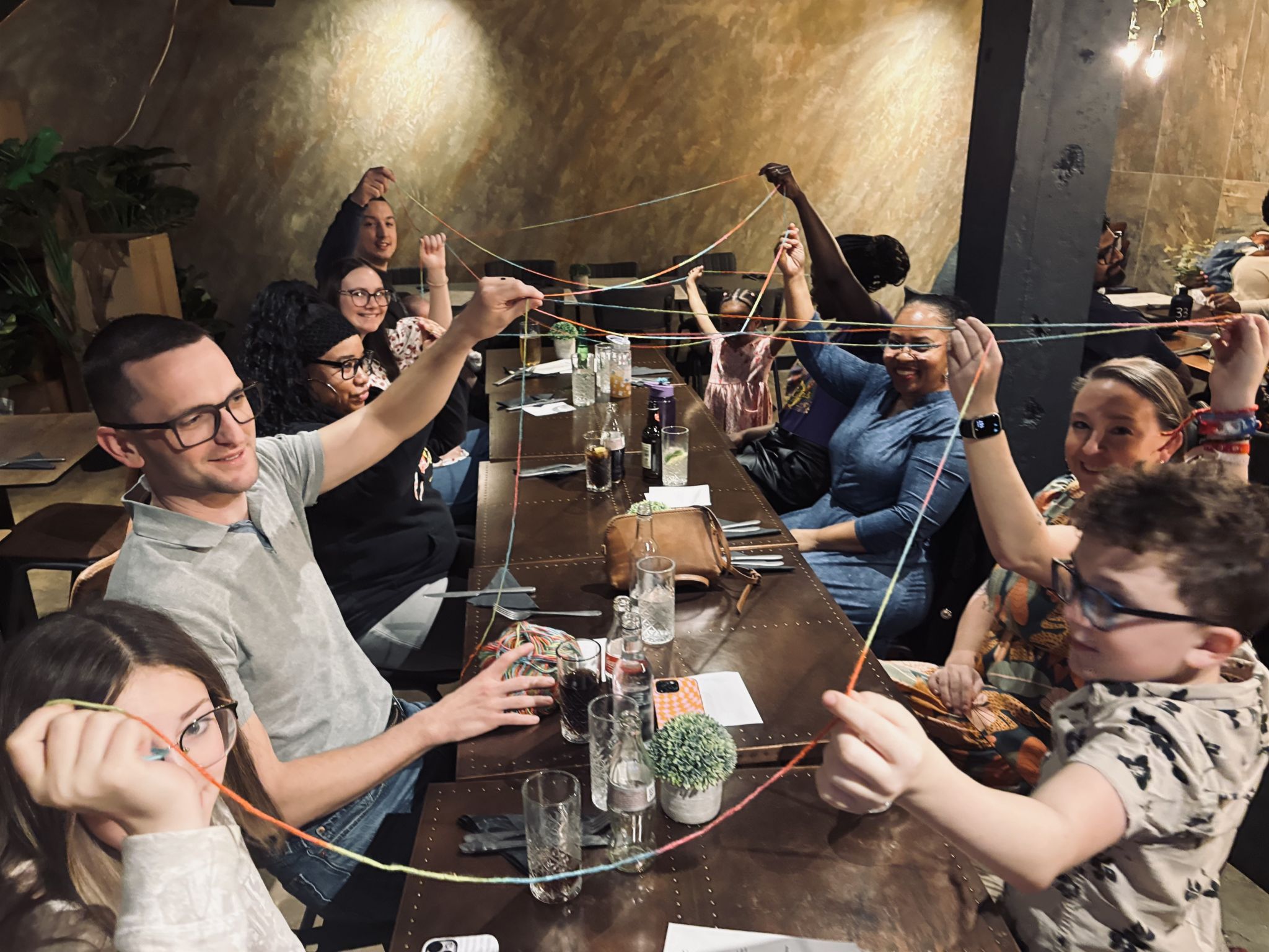 Members of a Beacon Church community group in Bury St Edmunds, Suffolk, taking part in a team-building activity around a table, building relationships, connection, and friendship within the church community.