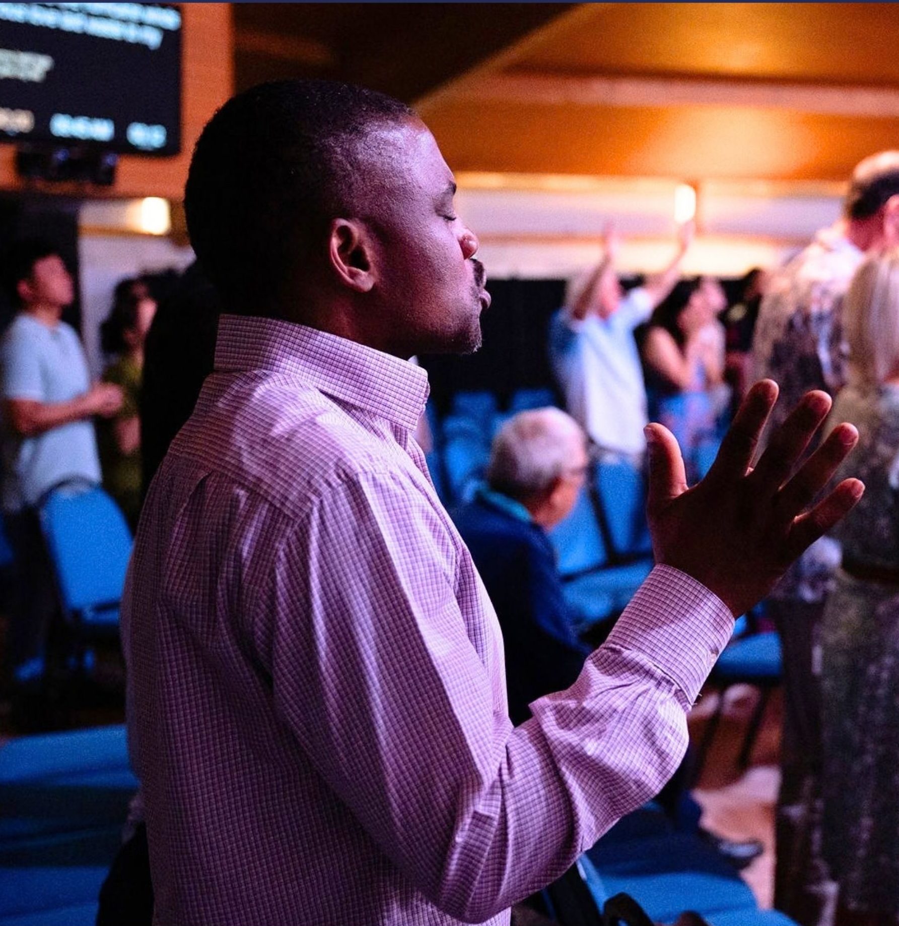 Man praying during a worship gathering at Beacon Church in Bury St Edmunds, Suffolk, as the church community comes together in prayer and worship.