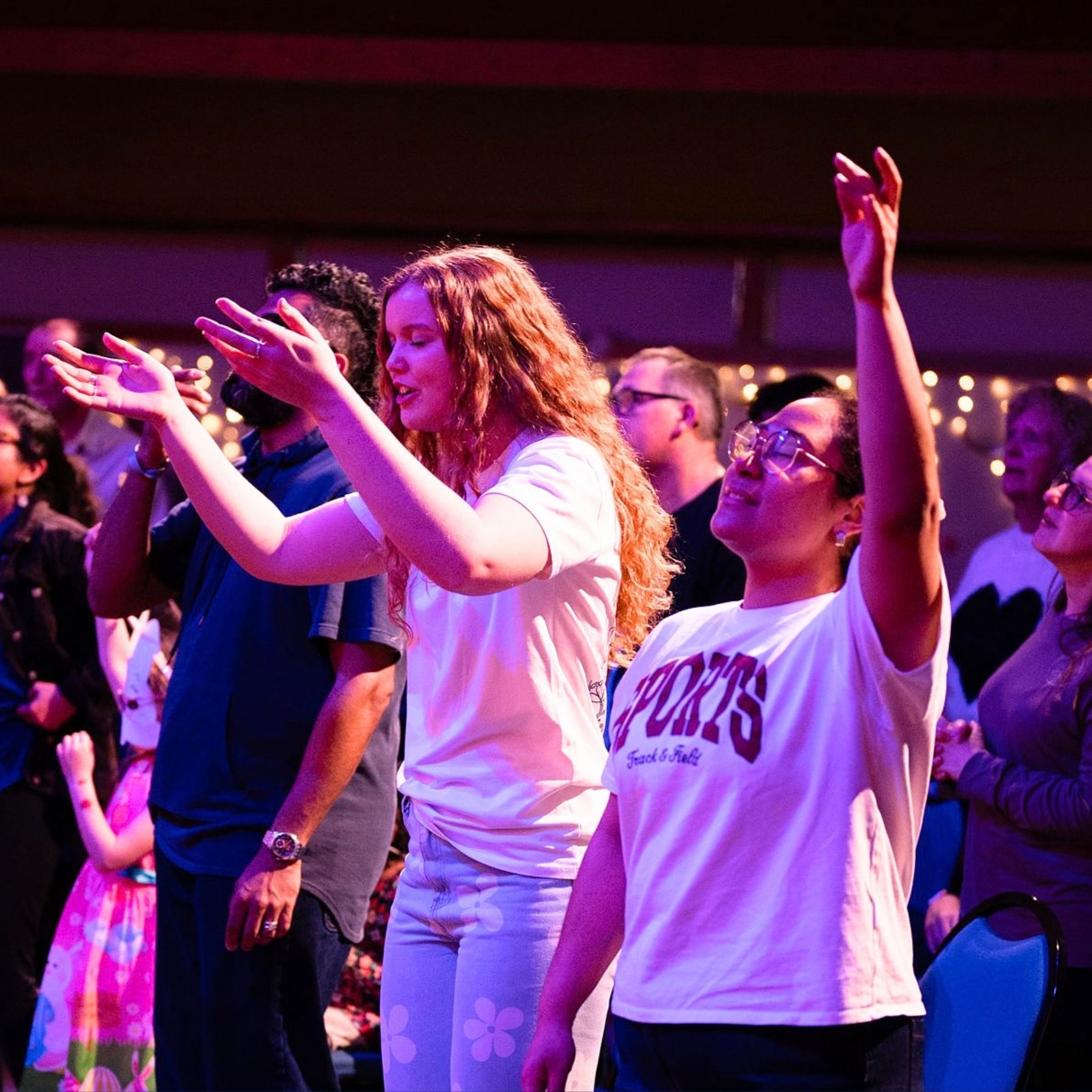 People worshipping with raised hands during a church gathering at Beacon Church in Bury St Edmunds, Suffolk.